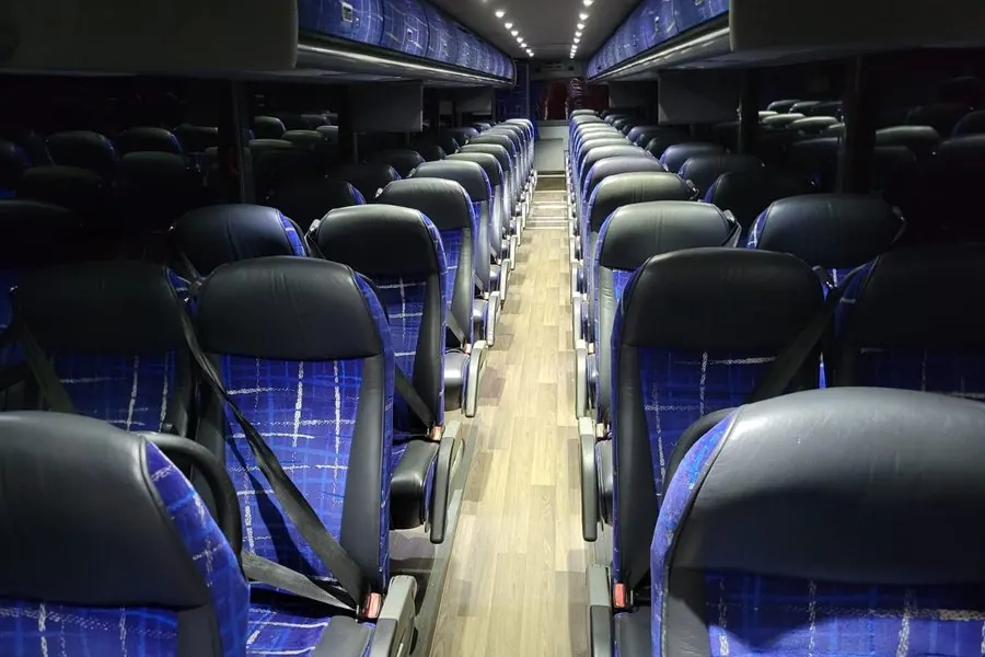 Motorcoach interior at night with blue LED cove lighting over black leather seats